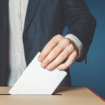 A man putting a voting slip into a box.