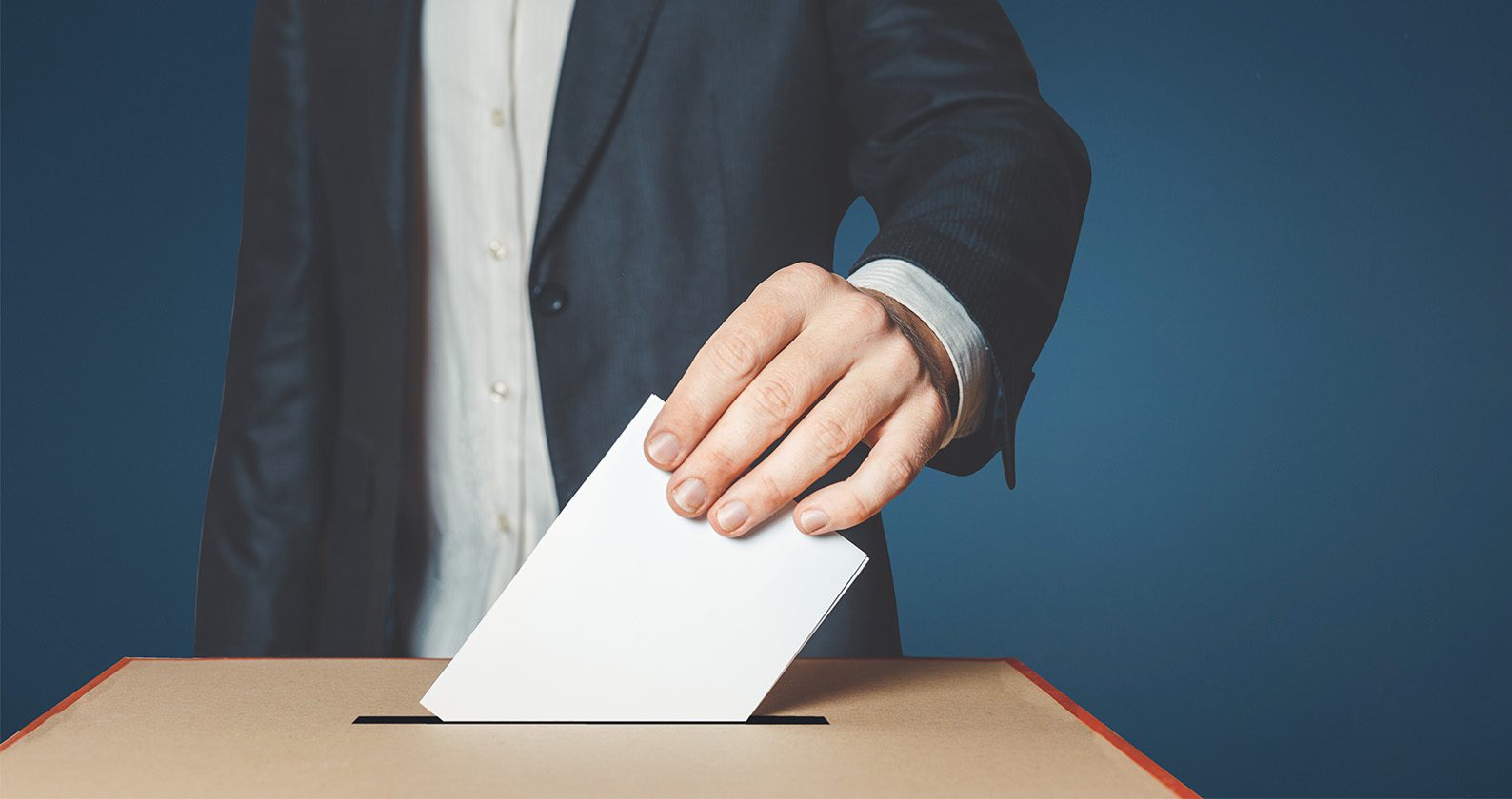 A man putting a voting slip into a box.