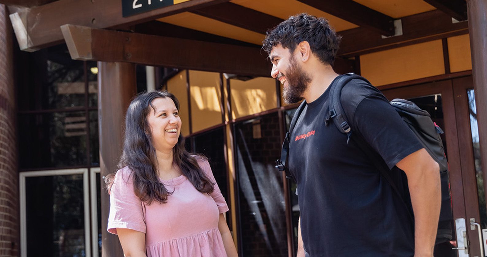 A male and female student having a conversation and laughing.