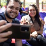 A male student taking a selfie on his phone with two female friends