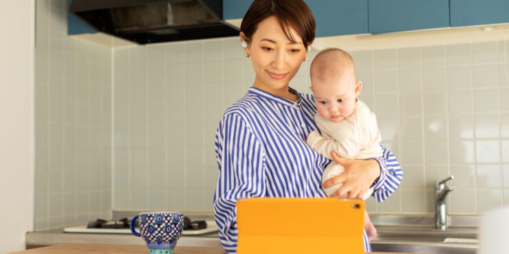 Mother holding infant using digital tablet