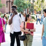 A diverse group of four students walking and smiling