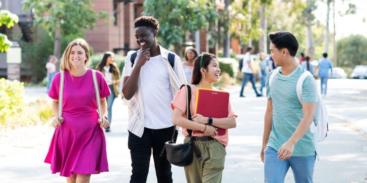 A diverse group of four students walking and smiling
