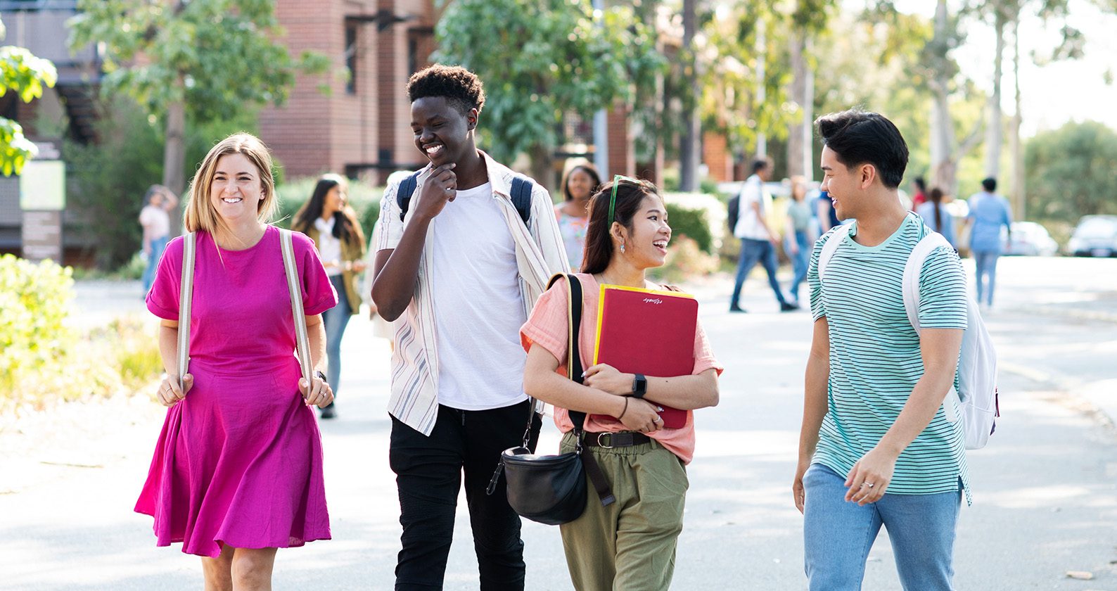 A diverse group of four students walking and smiling