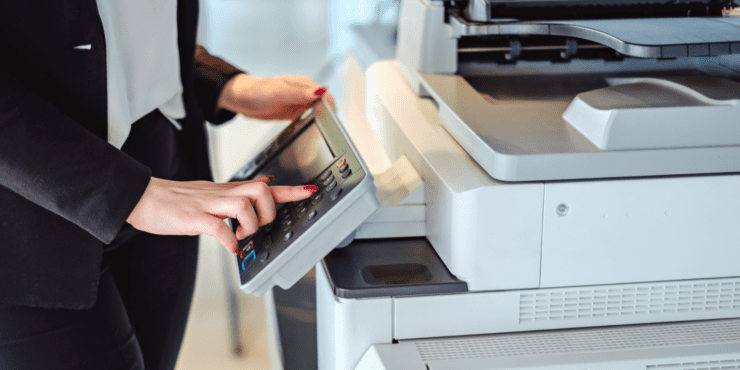 A female using a printer in an office.