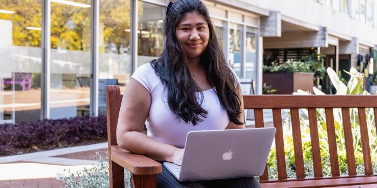 Person sitting on a bench on a laptop.
