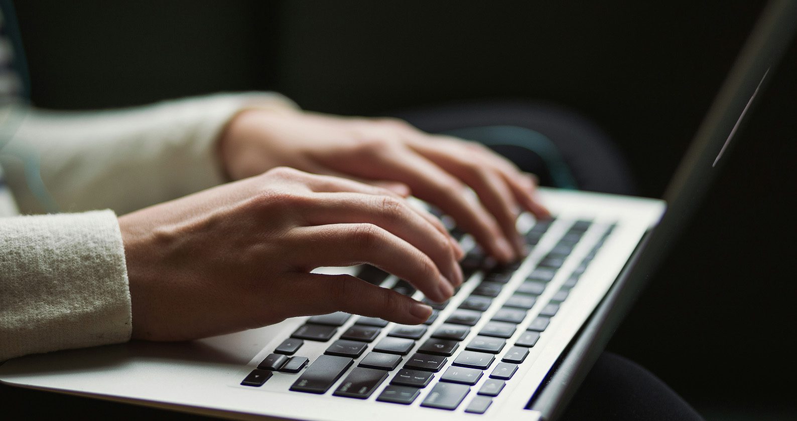 Persons hands typing on a laptop.