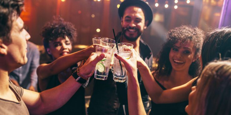 A group of students clinking glasses filled with liquid.