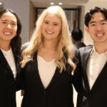 Three students wearing formalwear smiling.