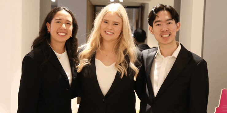 Three students wearing formalwear smiling.