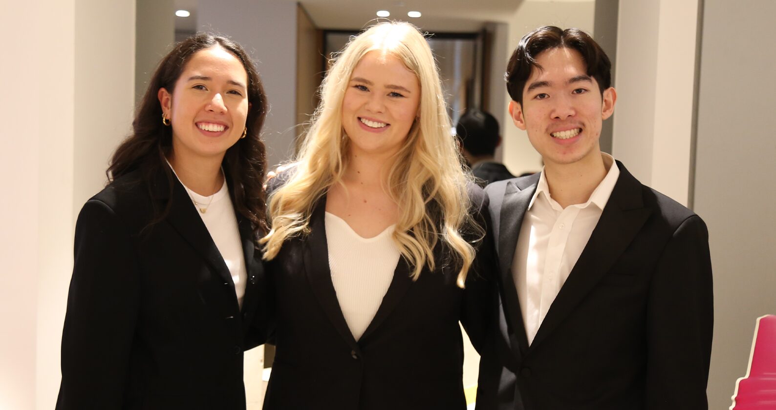 Three students wearing formalwear smiling.
