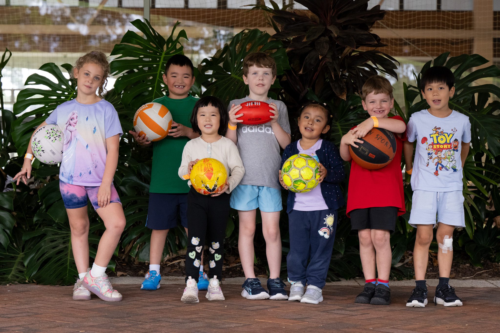Children smiling holding sporting equipment.