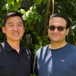 Shih Ching and Arash posing in front of a wall of greenery.