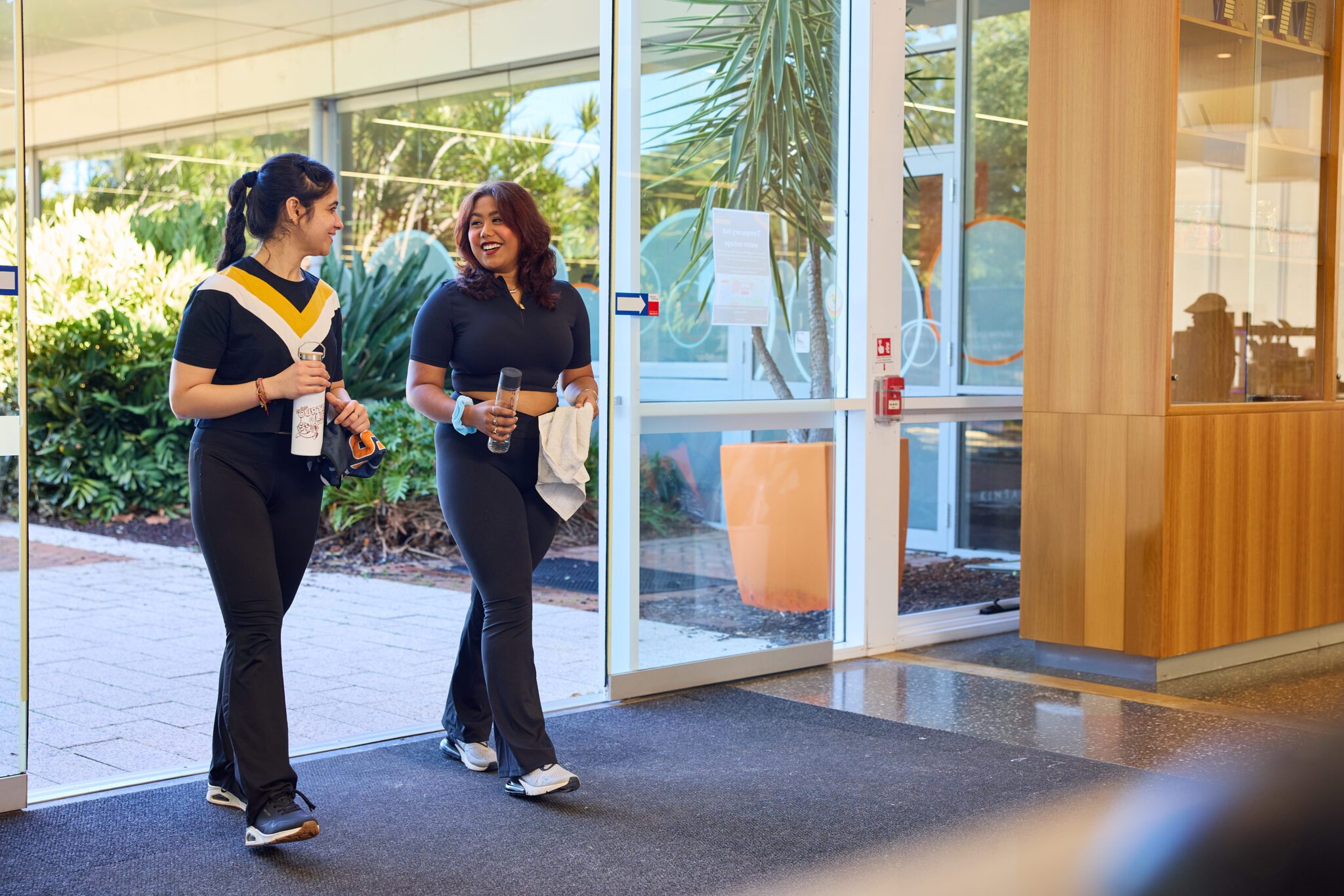 Two students walking into the Curtin Stadium reception area.