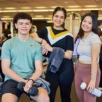 Three students smiling standing together in the Curtin Fitness Centre.