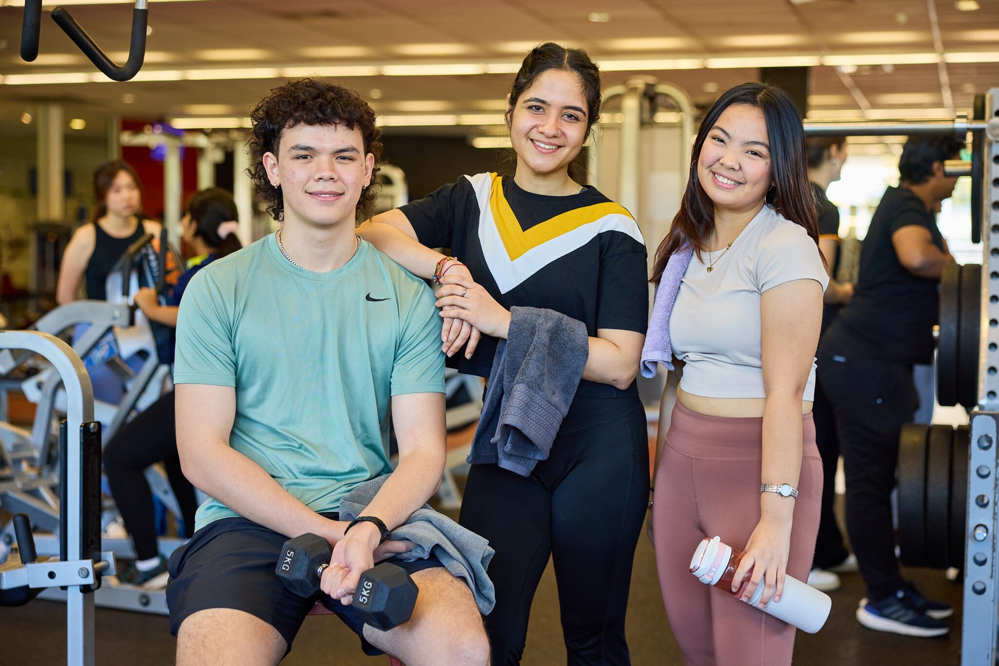 Three students smiling standing together in the Curtin Fitness Centre.