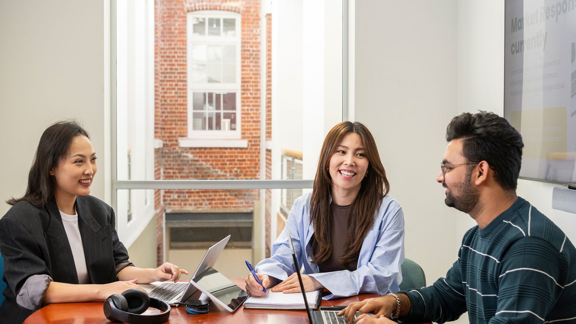 Three students brainstorm at a round table.