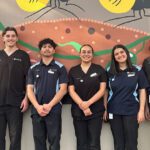 A group of rural placement students stand in a line smiling at the camera.