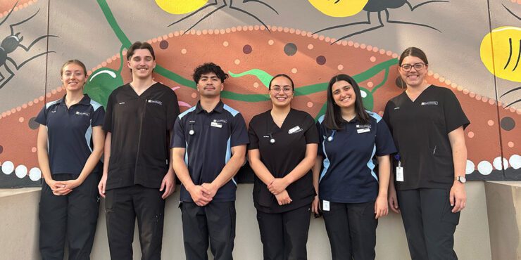 A group of rural placement students stand in a line smiling at the camera.