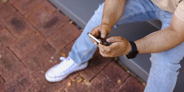 Student sitting on a step with a phone in their hands.