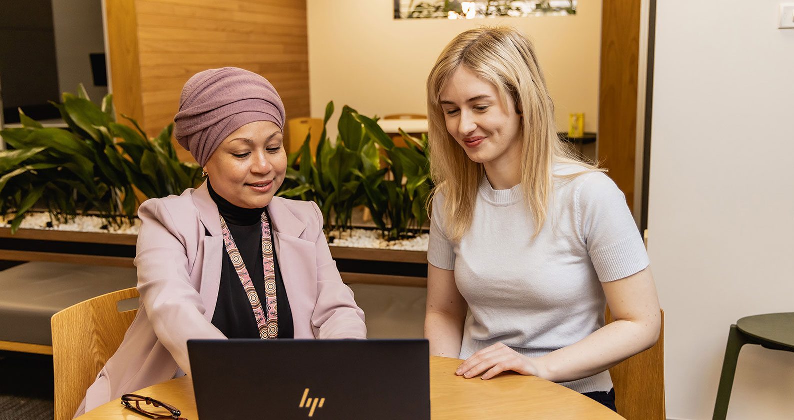 A student and staff member sitting at a laptop.