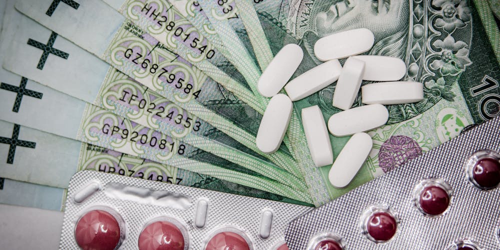 Polish 100 złoty notes with pills and blister packs, illustrating medical costs.