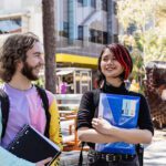 Two students holding books and smiling at each other.