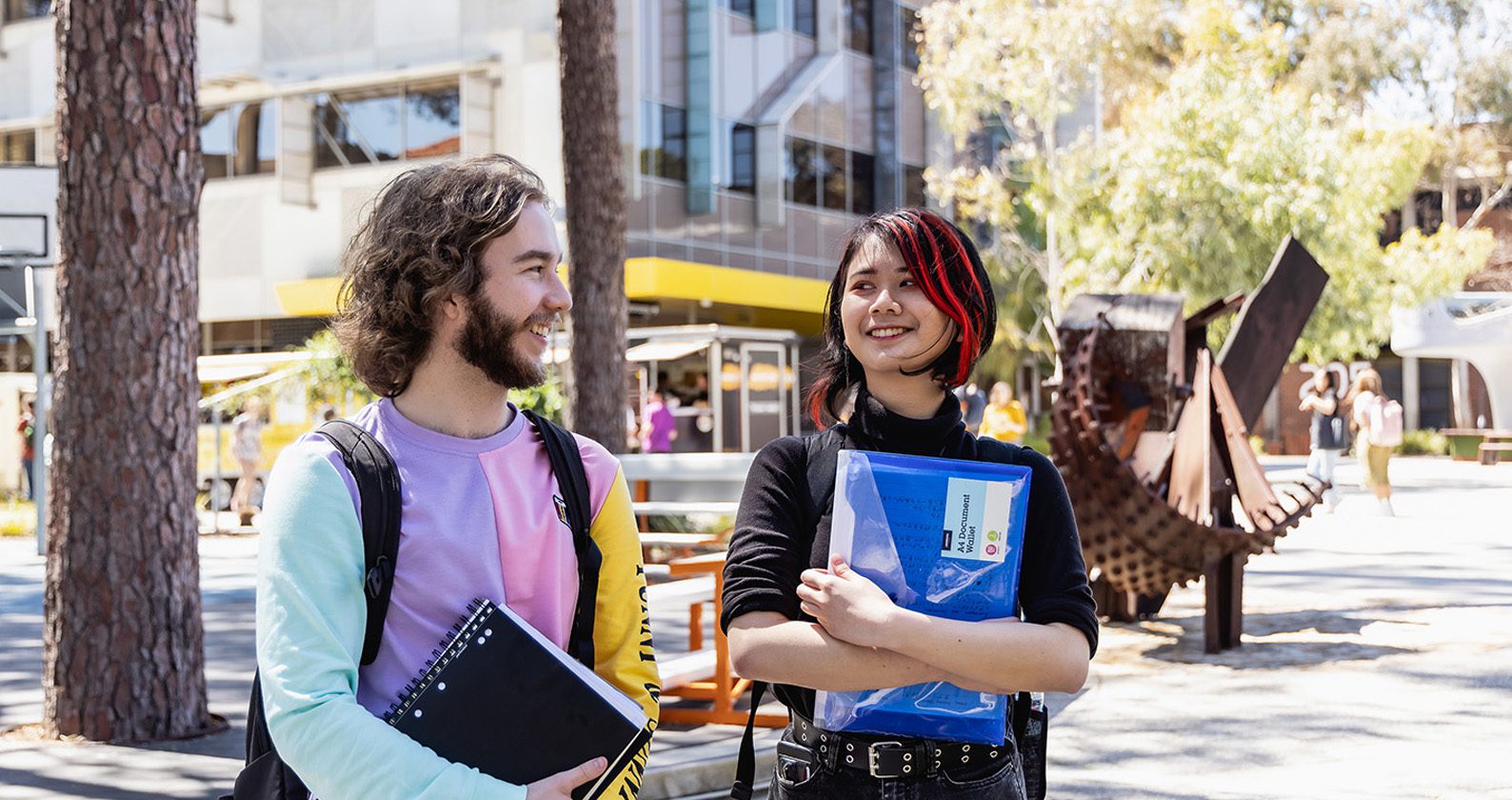 Two students holding books and smiling at each other.