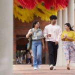 Three students walking together and holding coffee.