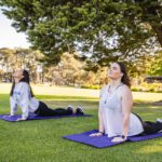 Two students on yoga mats on Edinburgh Oval.