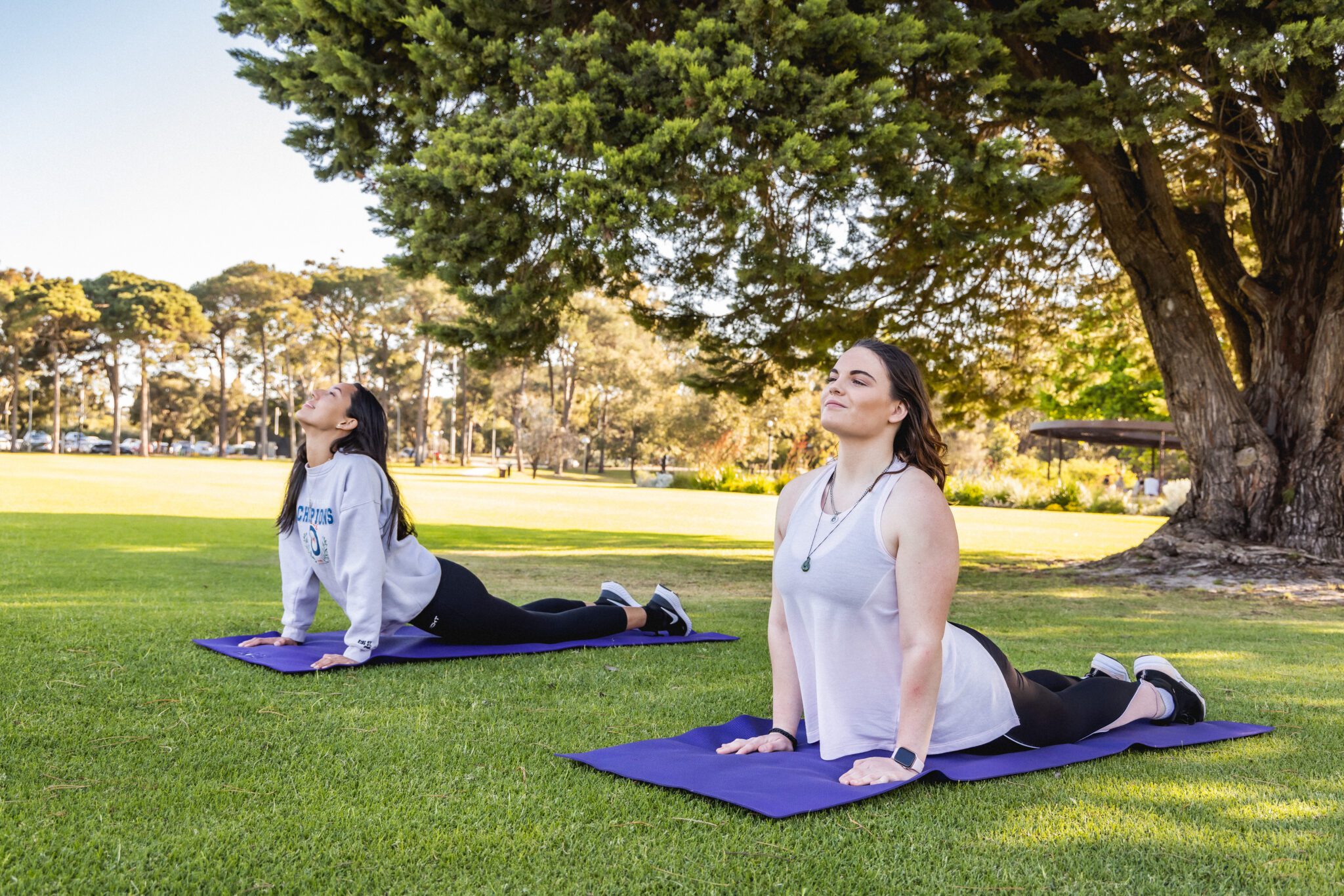 Two students on yoga mats on Edinburgh Oval.
