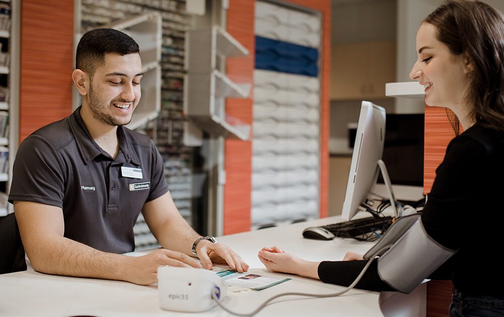 Two pharmacy students practice taking blood pressure.