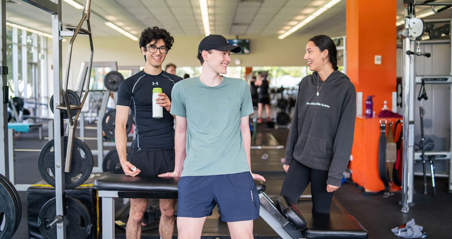 Three students in the Curtin Stadium gym surrounded by equipment.