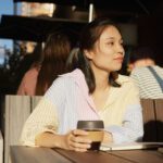 A student sitting and holding a coffee keep cup.