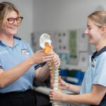 Two students holding a fake spine.