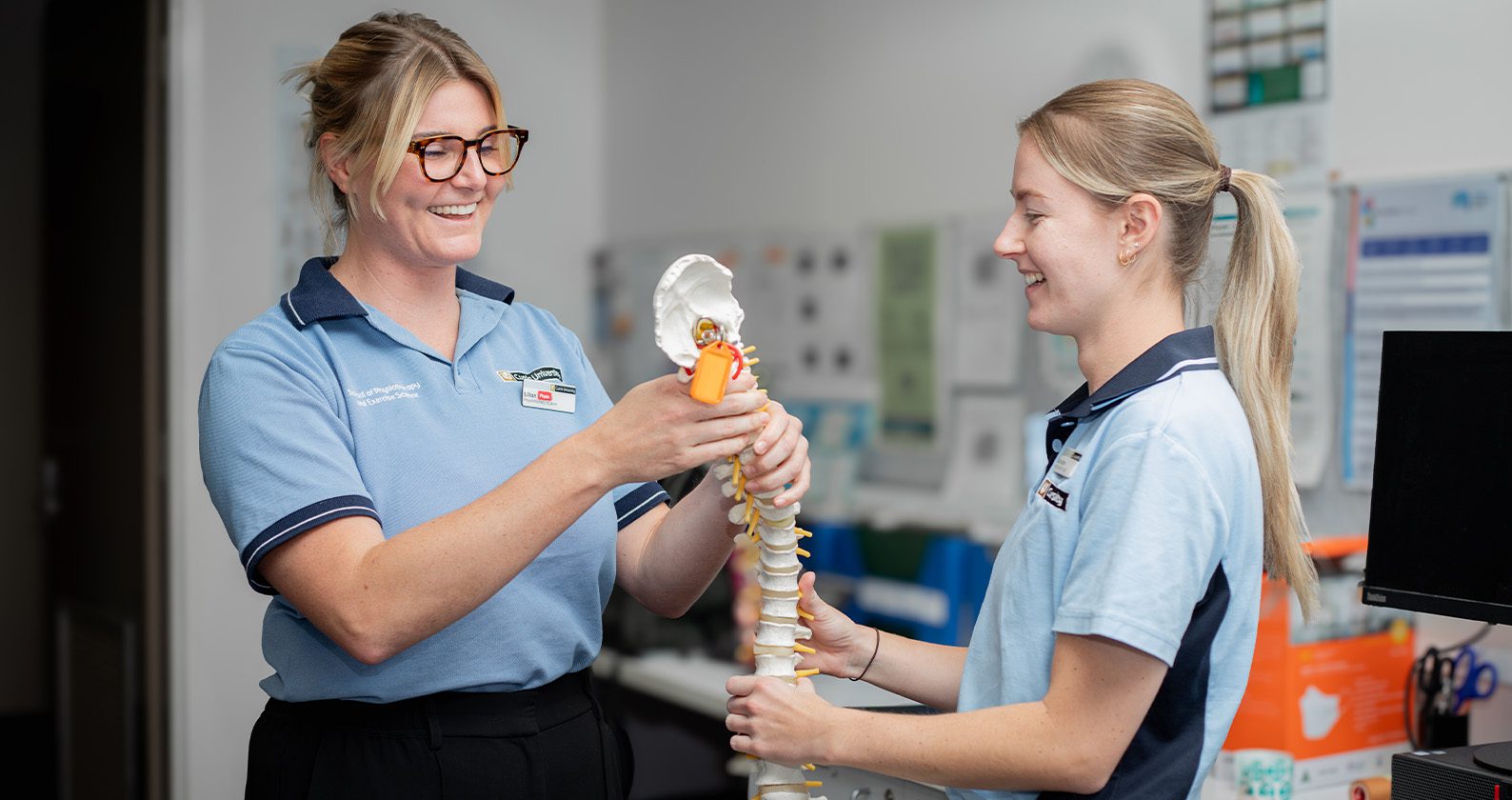 Two students holding a fake spine.