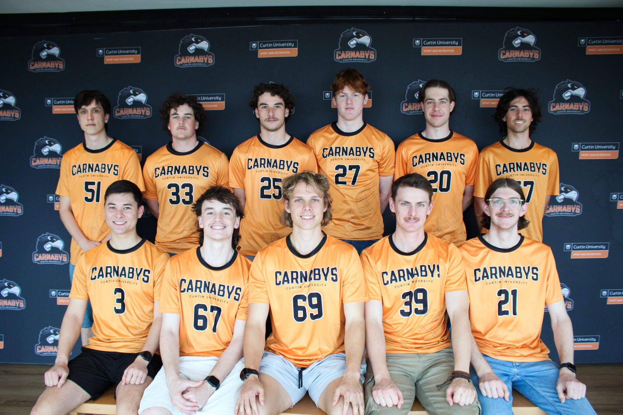 Curtin Carnabys team members smiling in front of a black backdrop.