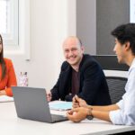 Three postgrad students sitting together at a white table.