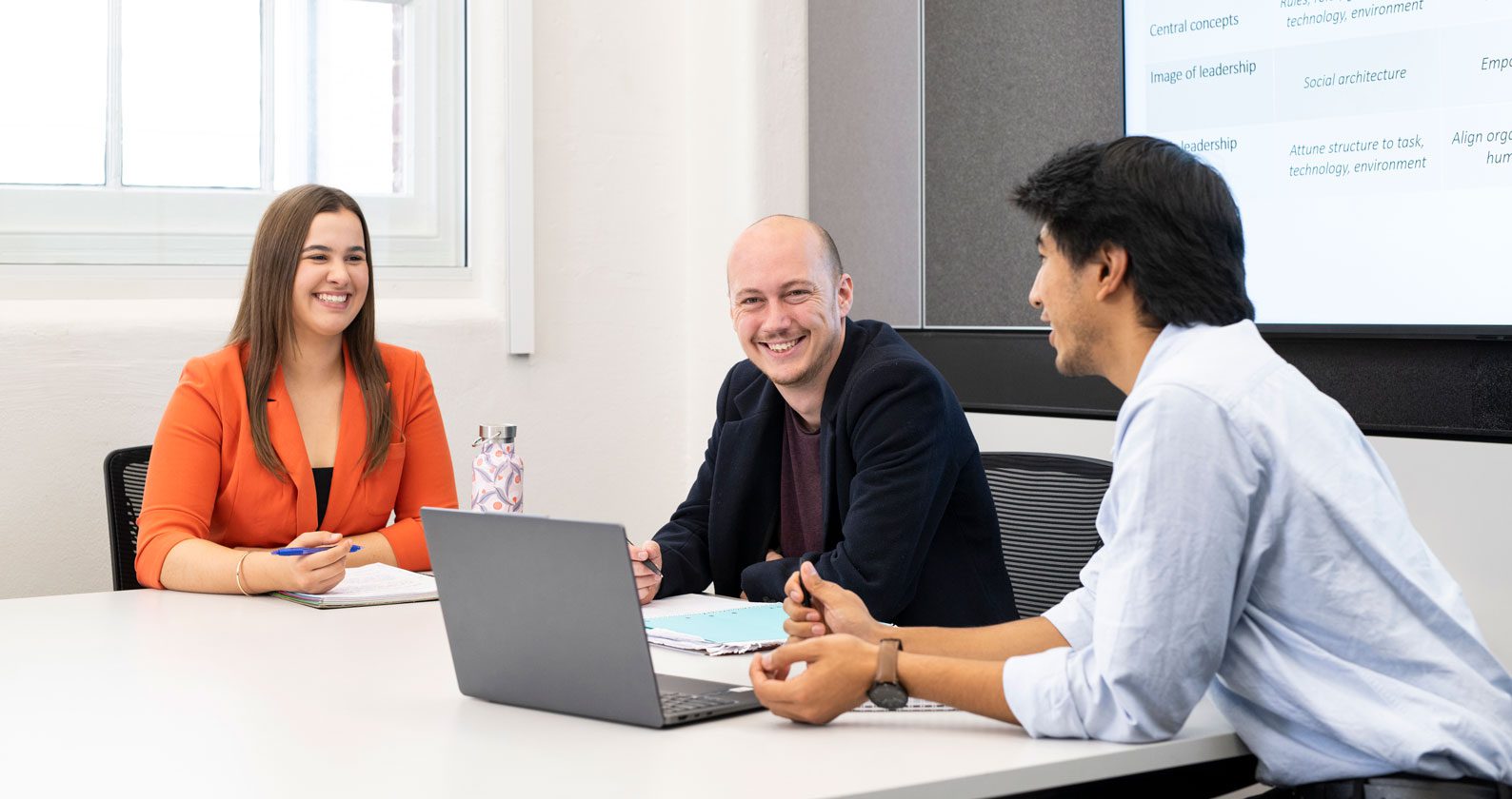 Three postgrad students sitting together at a white table.