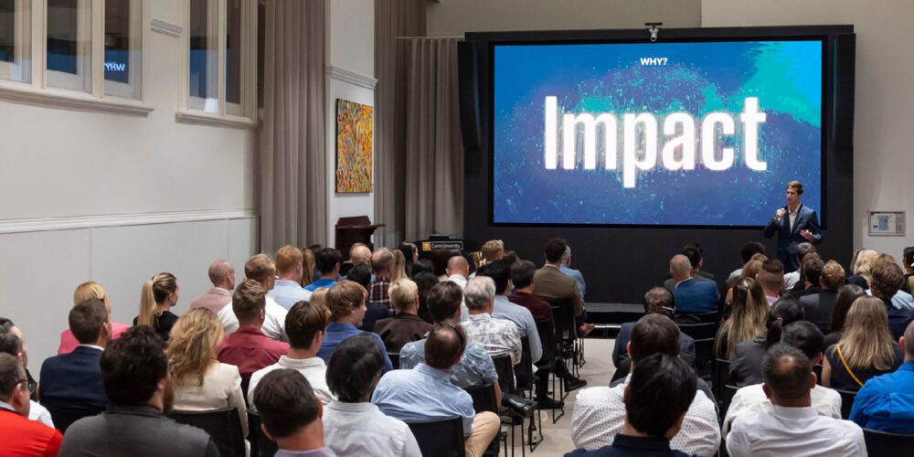 A crowd of people watching a powerpoint.