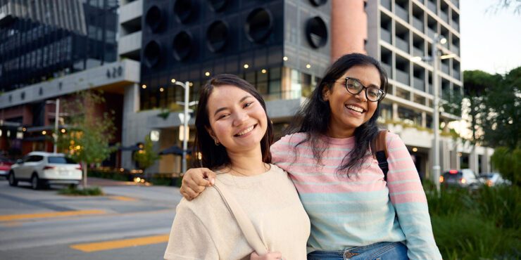 Two Curtin students smiling in front of their accommodation.