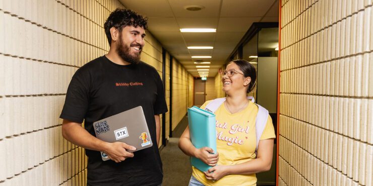 Two Indigenous students walk down a hallway.
