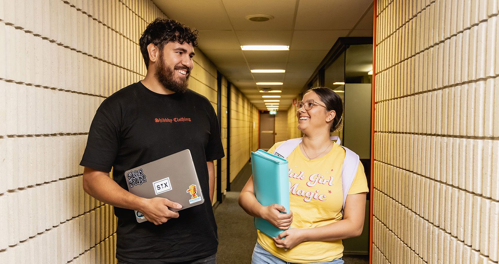 Two Indigenous students walk down a hallway.
