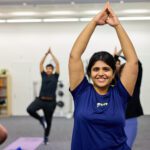 Image of a student wearing a blue top, doing a yoga pose.