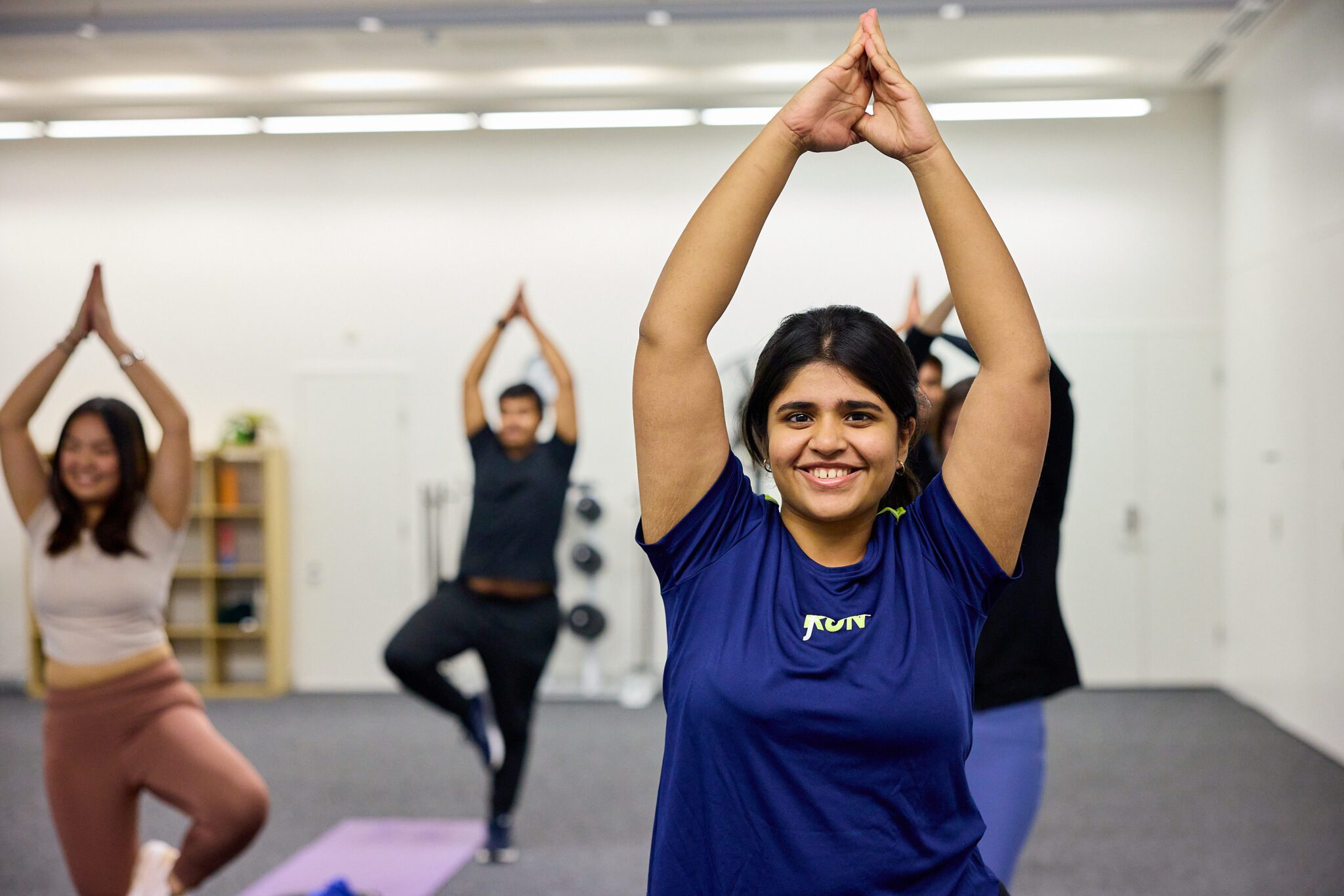 Image of a student wearing a blue top, doing a yoga pose.