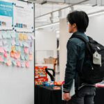 Person at a feedback hub with sticky notes, snacks and info tables.