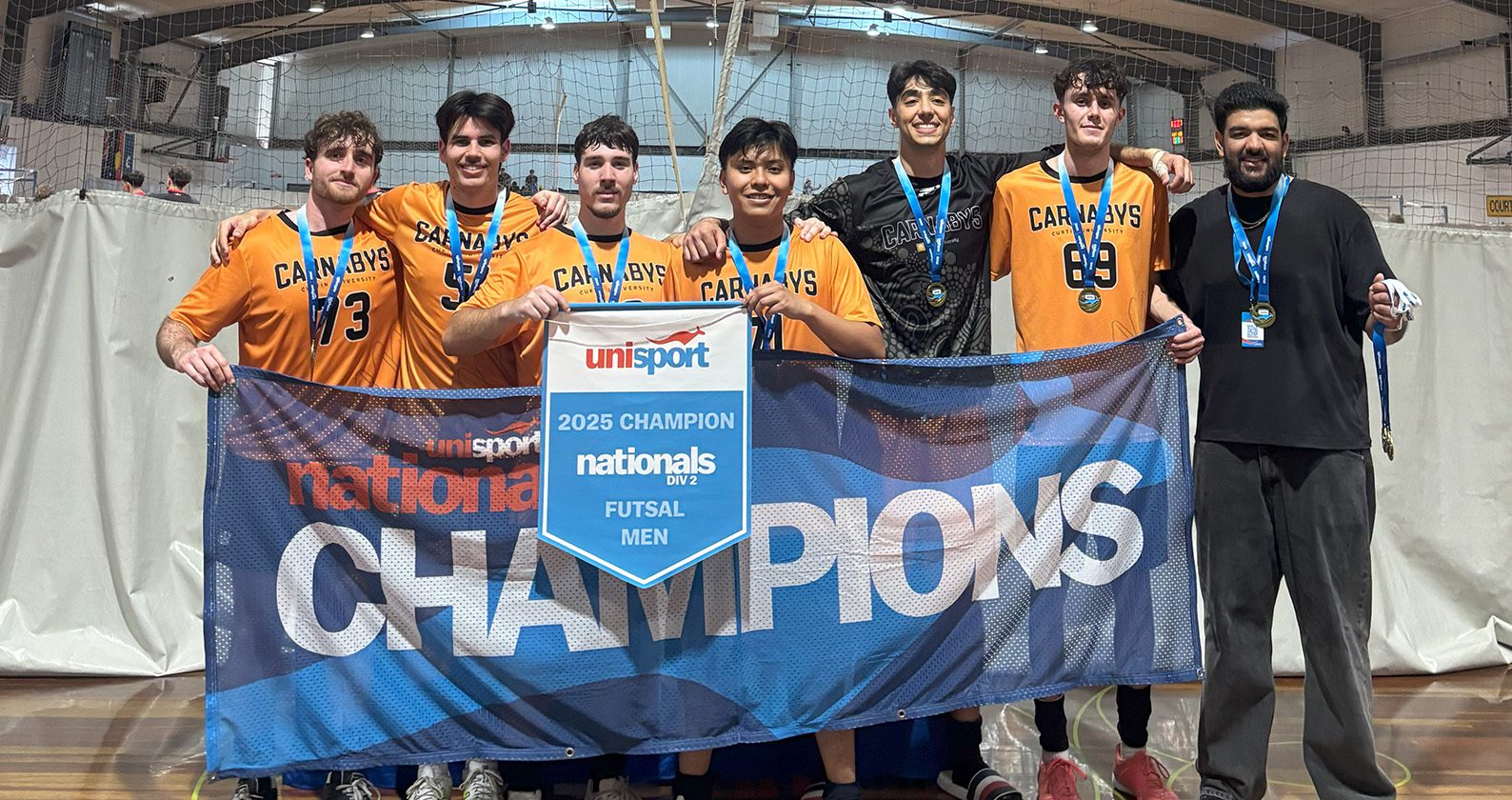 Curtin men’s futsal team holding a “2025 UniSport Nationals Division 2 Champions” banner.
