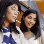 Two people working together at a table, looking at a laptop.