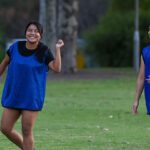 Two students in blue shirts on a field.