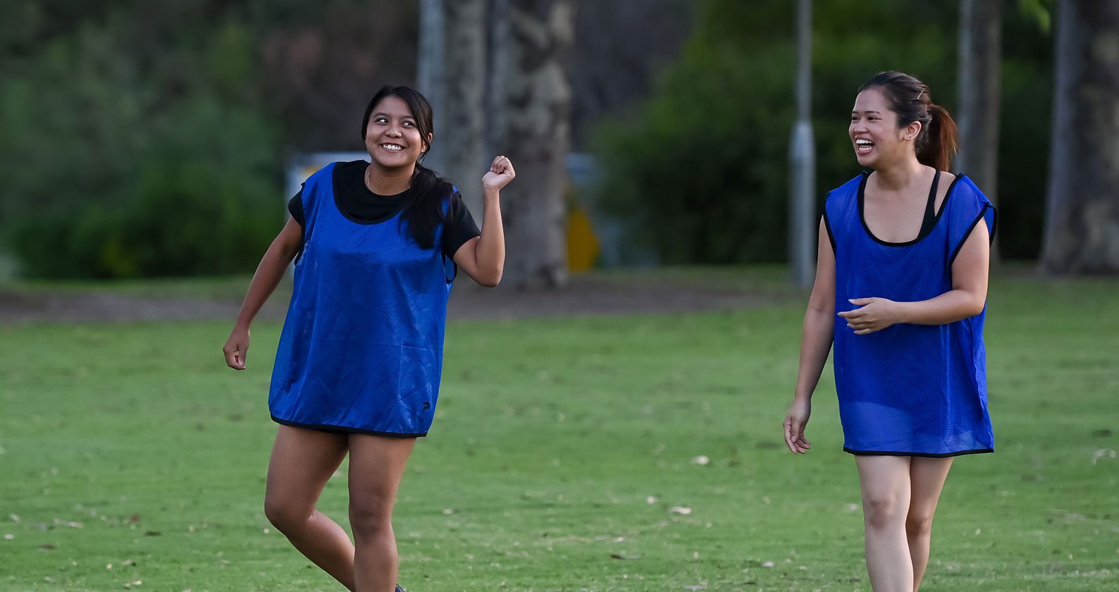 Two students in blue shirts on a field.